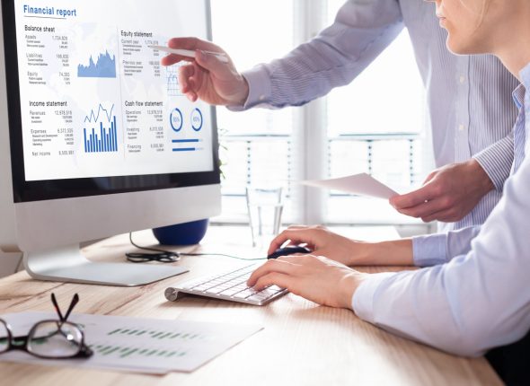 Consulting auditors auditing financial report on computer screen, business charts